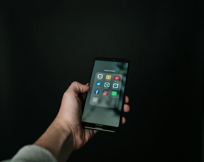 hand holding a phone showing different social media apps