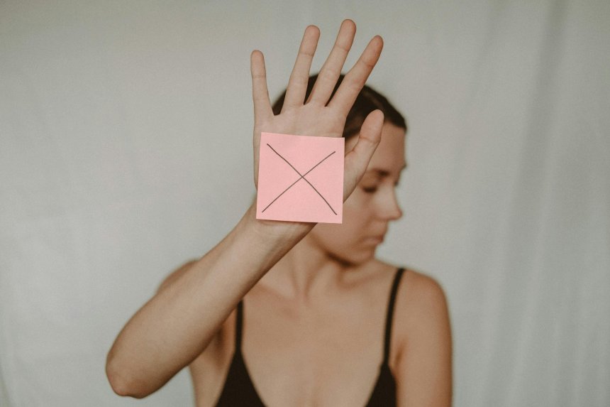 woman holding a note that shows a cross to say no