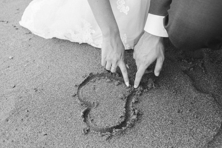 man and woman drawing a heart on sand