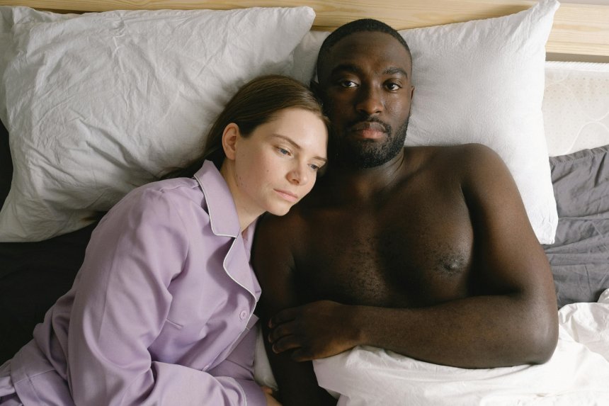 man and woman lying together unhappily